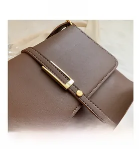 Close-up of vintage brown leather handbag with gold metal clasp and fine stitching detail