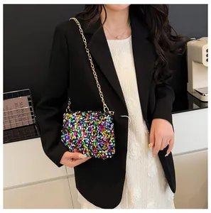 Detail of sequin bucket bag with gold chain strap on a model for a chic festive look