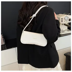 Detailed view of a white leather baguette bag with wavy stitching and knotted strap