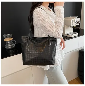 Détail du sac cabas noir à motif pied-de-poule gaufré sur un comptoir de café moderne