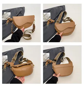 Detail view of brown saddle bag showing asymmetrical flap and wide woven strap