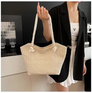Detailed close-up of beige straw tote bag with woven texture and white rope handles