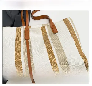 Detail of canvas tote bag showing vertical brown stripes and leather handle texture