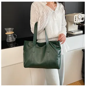 Dark green tote bag in textured faux leather carried by a woman in a white lace shirt