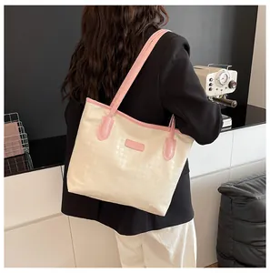 Détail du sac cabas gaufré pied-de-poule avec anses roses dans un décor moderne