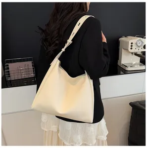 Detail view of large cream-white tote bag with wide adjustable strap on shoulder