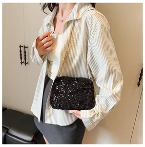 Detail view of black sequin bucket bag with gold chain strap on model's shoulder