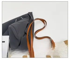 Close-up of reinforced stitching on brown faux leather straps of a striped tote bag