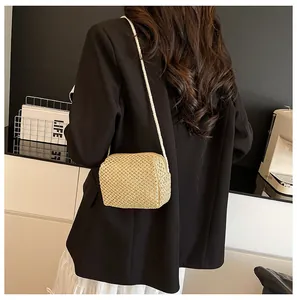 Detail of hand-woven beige straw bag featuring a refined honeycomb texture on a round crossbody