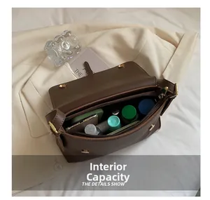 Detail of internal capacity in brown leather crossbody bag with golden magnetic buckle