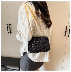 Detail of black sequined bucket bag with gold chain strap on shoulder for a stylish look
