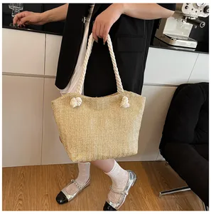 Detail of herringbone woven straw tote bag featuring thick cotton rope knotted handles