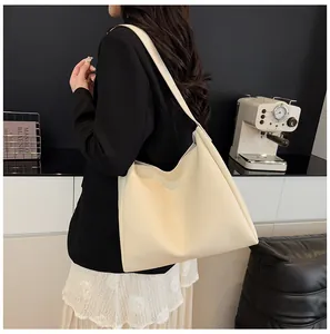 Detailed view of the creamy white large hobo tote bag worn by a model in a modern office