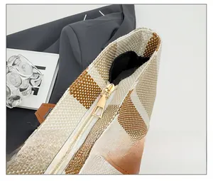 Detail of woven checkerboard tote with premium gold zipper and brown leather handle
