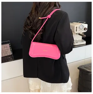 Detailed view of magenta faux leather shoulder bag with gold text and wave design