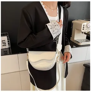 White faux leather saddle bag featuring dual straps and gold-toned metal hardware accents