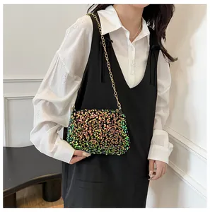 Close-up of a gradient sequin bucket bag with a fine gold chain strap on a model