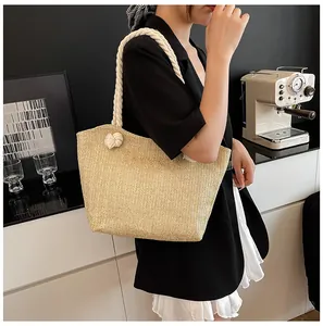 Detail of hand-woven straw tote bag with chunky cotton rope handle and knot decoration