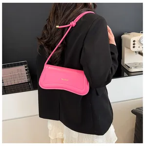 Detail of a bright pink leather underarm bag featuring a unique wavy bottom and gold logo