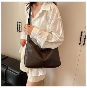 Close-up of dark brown tote bag showing supple leather texture and wide shoulder strap