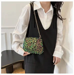 Detail of vibrant sequin crossbody bag with gold chain strap on a model outfit