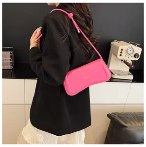 Close-up of a pink leather shoulder bag with gold XM BAGS logo and knotted strap detail
