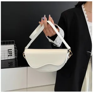 Detail of white saddle bag with wavy flap design and gold hardware hooks
