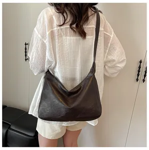 Detail view of large dark brown hobo tote bag in textured faux leather on model