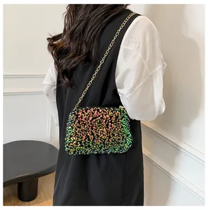 Detail of gradient sequin crossbody bag with gold chain strap on a model