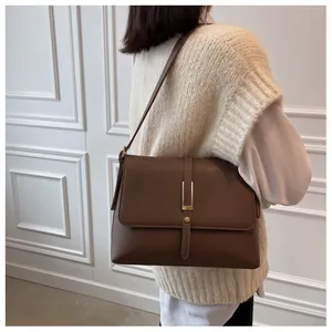 Detail view of a vintage brown leather shoulder bag with elegant gold metal buckle hardware