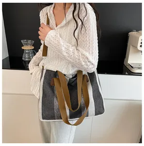 Detail der gestreiften Canvas-Tasche mit braunem Ledergriff und Gurt am Model
