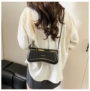 Detail of a sleek black leather crossbody bag with a gold logo and curved silhouette