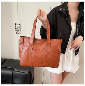 Detailed view of the caramel brown leather tote bag texture and reinforced double handles