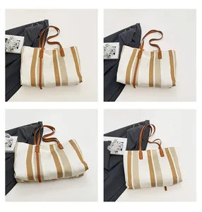 Detail of striped canvas tote bag with brown leather straps and vertical pattern