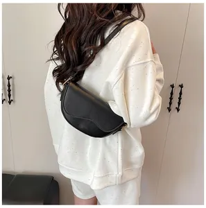Side view of black matte leather saddle bag with shoulder strap worn by a model
