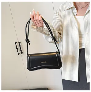 Detail of black leather shoulder bag with unique curved base and knotted strap buckle