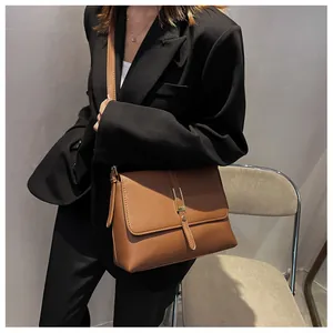 Close-up of a vintage brown leather shoulder bag with gold hardware worn on a model