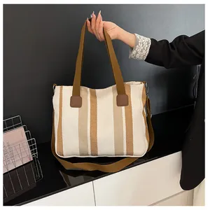 Detailansicht der gestreiften Canvas-Tasche mit braunen Lederflicken und Schultergurt