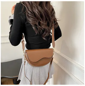 Rear view of model wearing a textured brown leather saddle bag with wide shoulder strap