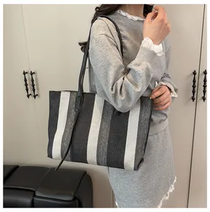 Vertical striped tote bag in black, white, and gray with sleek black leather handles