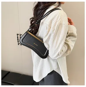 Detail of black leather shoulder bag with gold lettering and knot shoulder strap detail