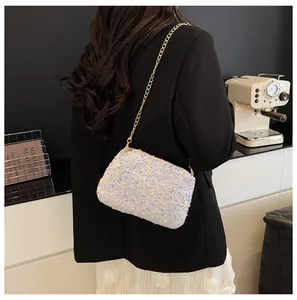 Close-up of stylish sequined bucket bag with gold chain strap on a black blazer