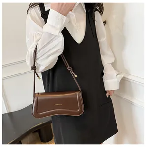 Brown leather underarm bag styled with a white embroidered shirt and black dress