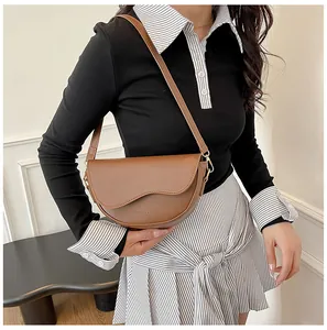Detail of brown leather saddle bag with wavy flap and adjustable shoulder strap