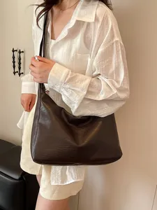 Minimalist deep brown soft leather tote bag worn by a model in a stylish casual setting