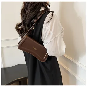 Detail of a brown leather shoulder bag with gold logo and decorative knotted strap