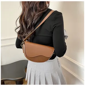Close-up of a brown leather saddle bag with wave edge design worn by a model