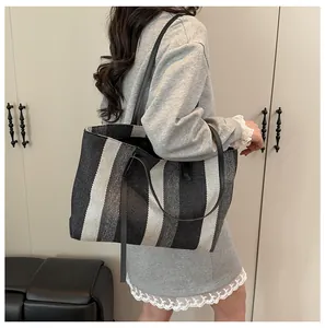 Detailed view of striped tote bag with leather straps and elegant tassel on model