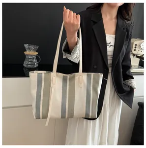 Close-up of canvas tote bag with vertical stripes and leather reinforced handles