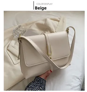 Detail view of the beige minimalist crossbody bag with golden rectangular hardware buckle